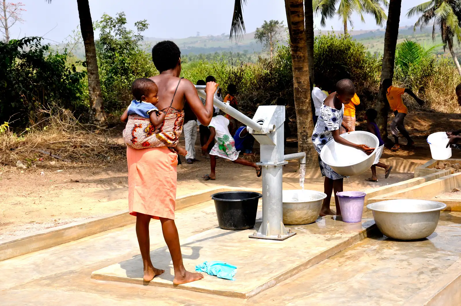 Families collecting water at a hand pump